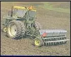 Tractor pulling a harvesting combine over brown dirt