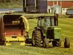 Tractor pulling a harvesting combine through short fields of grass