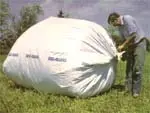 Someone tying up a white bag full of farming materials
