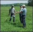 Group of farmers standing around a grassfield discussing